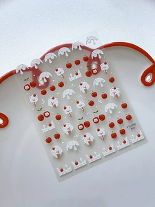 Macro detail of 3D embossed nail stickers featuring cute cherries and cat ice cream motifs
