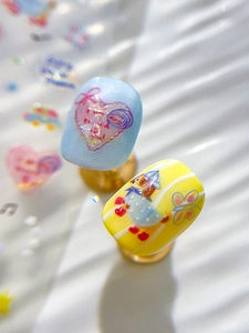 Macro shot of colorful handmade press-on nails with blue heart and yellow duck designs