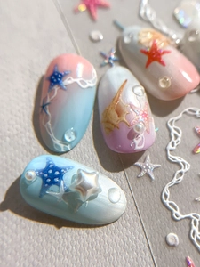 Macro detail of 3D starfish and shell charms on gradient ocean-themed nail art stickers