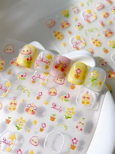 Detail shot of 3D embossed yellow duck nail stickers on tips with cute cartoon floral patterns