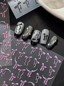 Détail d'autocollants nœuds violets 3D avec perles sur ongles noir et argent pailleté
