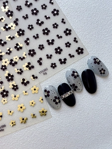 Detail of floral nail stickers with black and gold designs and rhinestone accents