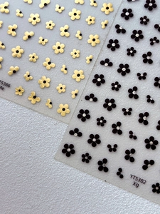 Macro detail of 3D gold and black floral nail stickers with mini rhinestone accents