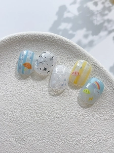 Detail view of cute rain drop and rainbow nail art stickers on short square oval fake nails