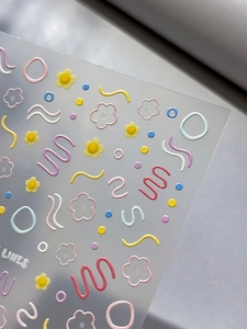 Vue macro d'autocollants 3D pour ongles avec fleurs pastel et lignes ondulées colorées