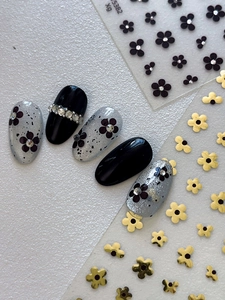 Macro detail of press-on nails with silver floral patterns and rhinestone accents