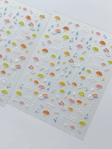 Detailed close-up of rainbow and rain drop nail stickers with cute cloud patterns