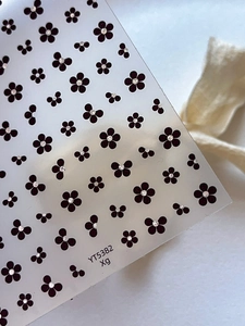 Close-up of minimalist black five-petal flower nail stickers with white center dots