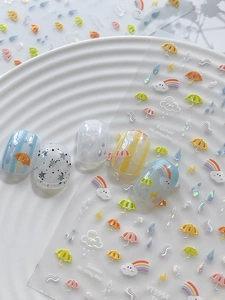 Detailed view of rainbow and umbrella nail art stickers with 3D texture on clear tips