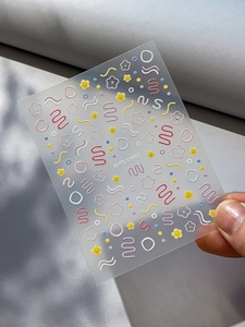 Vue macro de stickers ongles 3D avec des fleurs colorées et des lignes mignonnes