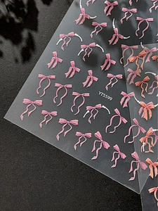 Vue macro de stickers nail art 3D gaufrés avec nœuds roses et détails de perles
