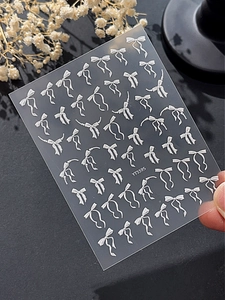 Vue détaillée de stickers 3D gaufrés blancs en forme de nœuds avec perles pour ongles