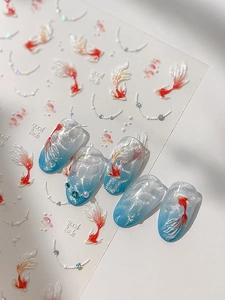 Detail of koi fish and pearl nail stickers on blue gradient manicure featuring good luck text