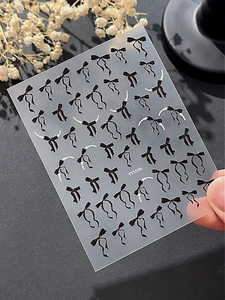 Vue macro de stickers ongles nœuds noirs en relief 3D avec détails de perles