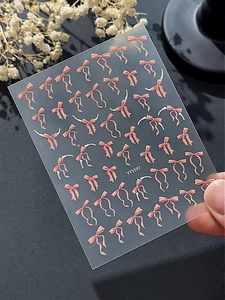 Vue macro d'autocollants 3D pour ongles à nœud rose avec détails de chaîne perles