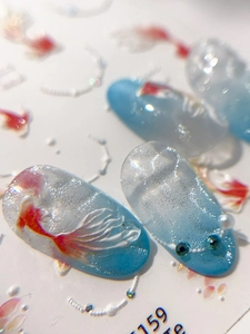 Macro detail of 3D goldfish nail art stickers with glitter and pearl embellishments