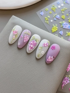 Close-up of 3D embossed purple grape and floral nail art designs on pastel tips