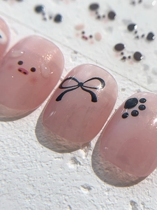 Close-up of pink jelly press-on nails featuring cute cartoon pig and black bow designs