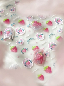 Detail of sweet strawberry and blue bow nail art stickers on pink checkered nails