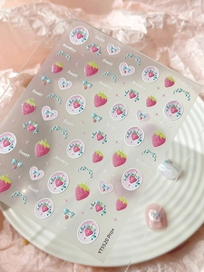Macro detail of YT5520 Pro strawberry and bow nail art stickers on a pink background