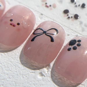 Handmade press-on nails with jelly pink base, cute pig motifs and black ribbon accents