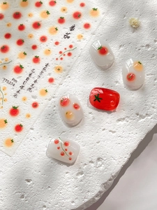 Detail view of tomato themed nail art stickers with sample display on white nails