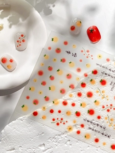 Detail showing fresh red and yellow tomato pattern nail stickers on glossy almond tips