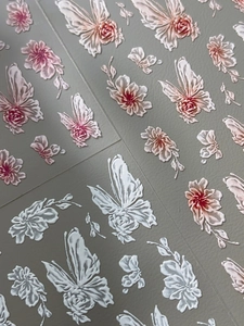 Macro detail of 3D embossed nail stickers featuring white rose and butterfly patterns