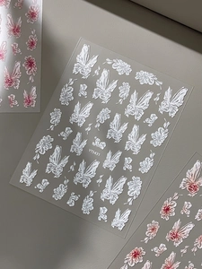 Macro detail of 3D embossed nail art stickers featuring elegant butterfly and floral patterns