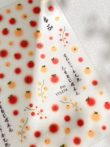 Macro detail of tomato themed nail art stickers with red patterns and green vines