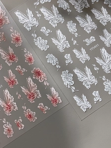 Detailed macro view of 5D embossed nail stickers featuring floral and butterfly designs
