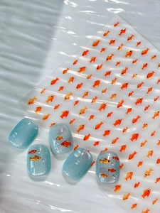 Detail of orange goldfish nail stickers on light blue cat eye nails with water drop effects