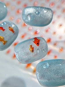 Macro shot of translucent blue jelly nail art charm with glitter and fish patterns