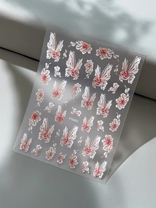 Macro view of 3D embossed butterfly and flower nail art stickers on a textured background