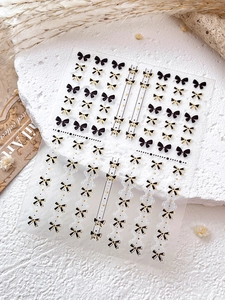 Stickers à ongles nœuds noirs avec bordure dorée et motifs dentelle sur pierre blanche