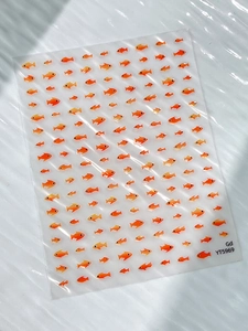 Macro detail of transparent orange goldfish nail art stickers with glossy finish