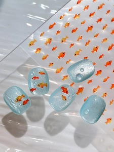 Detailed macro view of 5D embossed goldfish nail stickers on light blue cat-eye polish