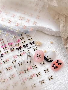 Vue détaillée des autocollants à ongles nœuds 3D avec motifs dentelle noirs et roses