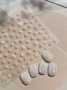 Detailed view of cat paw nail art stickers with pink and white patterns and sample nails