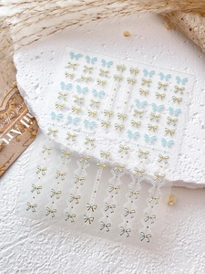 Détails d'autocollants pour ongles double nœud en bleu clair et blanc bordés d'or