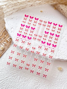 Détail de stickers ongles nœud rose avec dorure et motifs dentelle sur pierre blanche