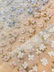 Macro detail of 3D embossed floral nail stickers with gold foil edges and petal textures