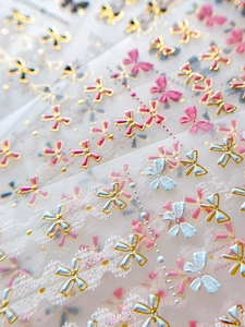 Vue macro de stickers ongles nœuds roses avec cadres dorés gaufrés et motifs dentelle