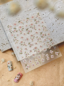 Detail of pink cherry blossom nail stickers with gold edges on white and pink nails