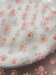 Detailed macro view of cute coral pink cat paw pattern on a pearl white decorative sticker