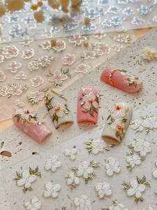 Detailed 3D embossed floral nail stickers with gold edges on white marble background