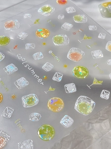 Close-up of summer nail art stickers with laser glitter lemon and ice cube patterns