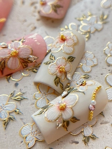 Macro shot of 3D embossed floral nail stickers with gold edges and pearl accents