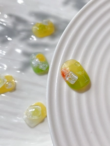Close-up of 3D summer lemon and ice cube resin nail art charms with jelly texture