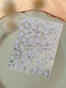 Detailed close-up of blue floral nail art stickers on a decorative ceramic plate